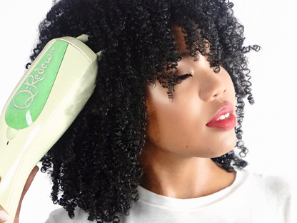 A woman with 4C curly hair holding a Q-Redew handheld hair steamer